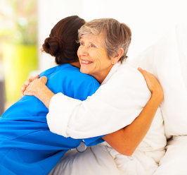 caregiver and old woman hugging each other